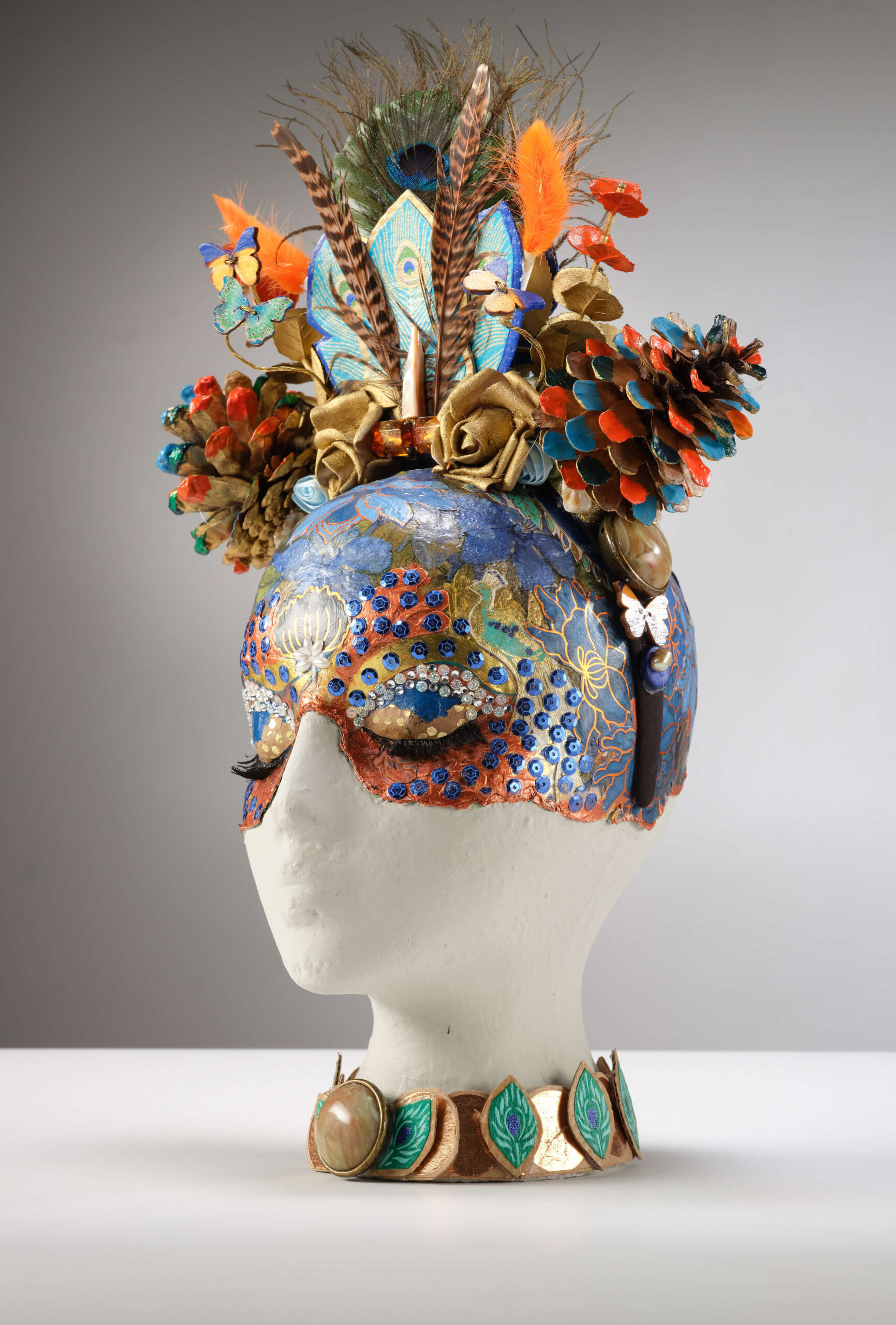 "Headdress with Harmonized mannequin head" peacock and pinecones, close view, by Emma Mullender